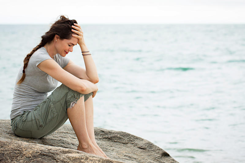 Eine einsame Frau sitzt traurig am Meer
